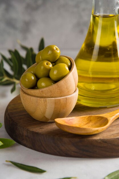 Aceitunas y aceite de oliva sobre tabla de madera con tazón de fuente gris