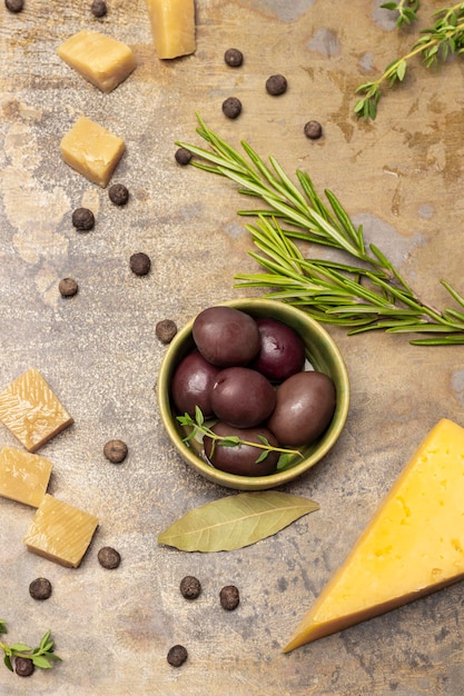 Aceitunas en un bol una ramita de romero y trozos de queso