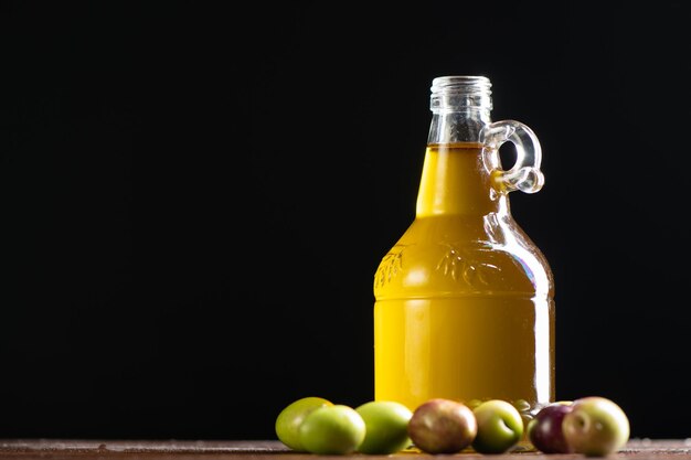 Aceitunas y una botella de aceite de oliva sobre negro cerrar