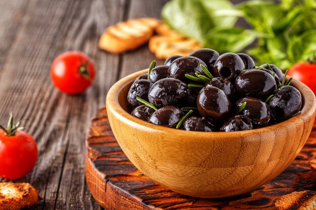 Aceitunas frescas con baguette tostado sobre una tabla de madera