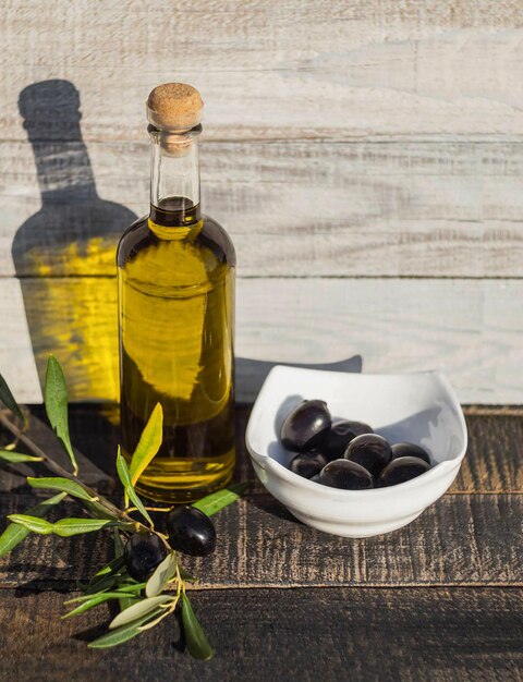 Aceitunas negras y una botella con aceite de oliva griego natural un fondo de madera en Grecia