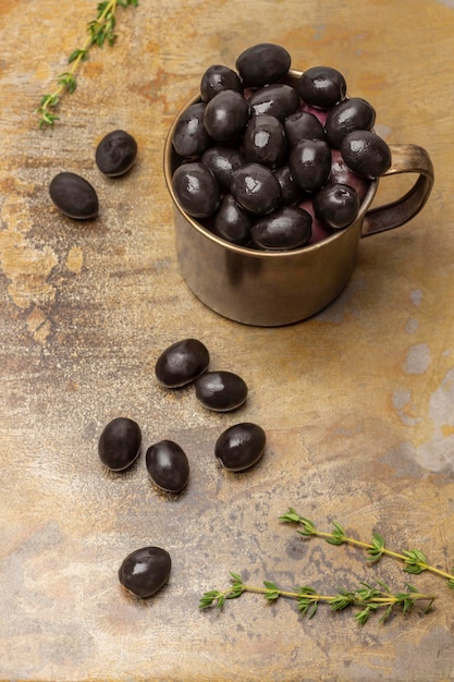 Aceitunas negras en una taza de metal y sobre la mesa