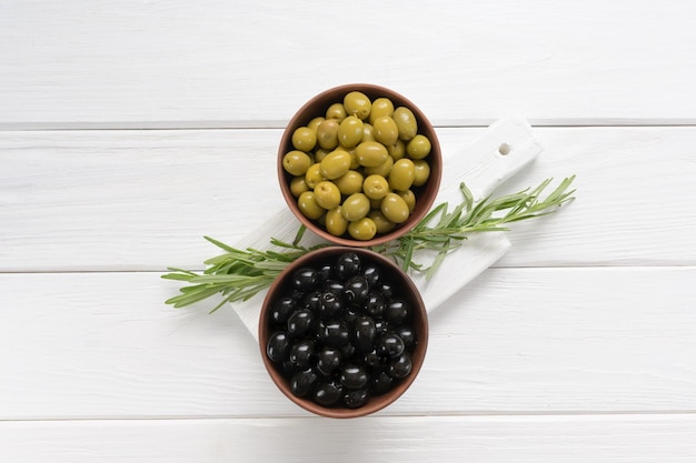 Aceitunas negras y verdes sobre un fondo blanco de madera