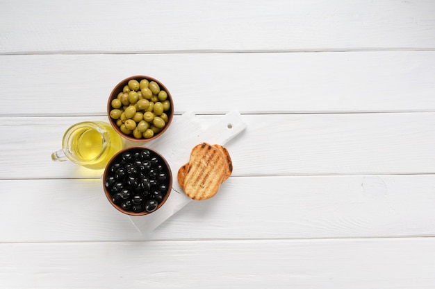 Aceitunas negras y verdes sobre un fondo blanco de madera