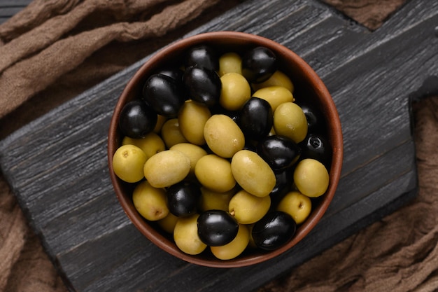 Aceitunas negras y verdes sobre un fondo negro de madera oscura