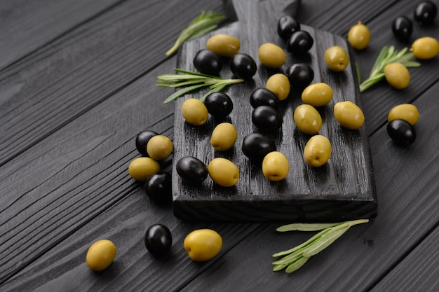 Aceitunas negras y verdes sobre un fondo negro de madera oscura