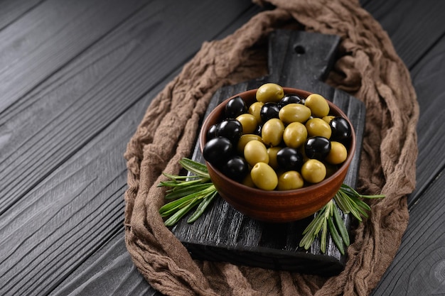 Aceitunas negras y verdes sobre un fondo negro de madera oscura