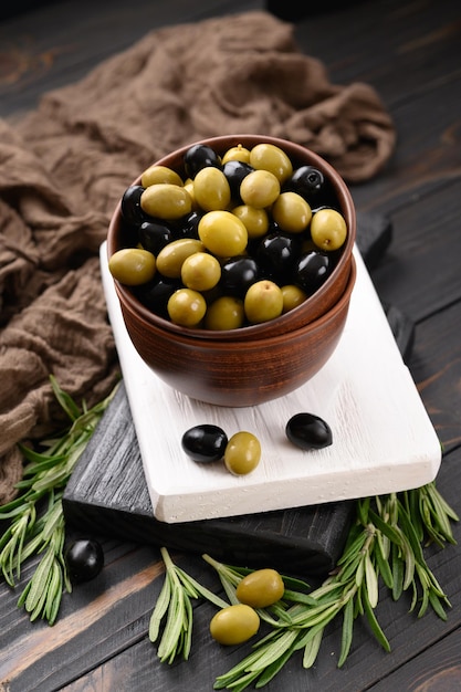 Aceitunas negras y verdes sobre un fondo rústico de madera oscura