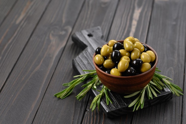 Aceitunas negras y verdes sobre un fondo rústico de madera oscura