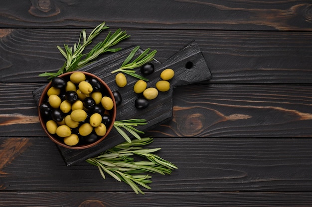 Aceitunas negras y verdes sobre un fondo rústico de madera oscura