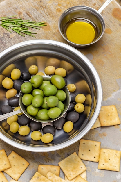 Aceitunas negras y verdes en tazones de metal Mantequilla en un tazón y galletas en la mesa