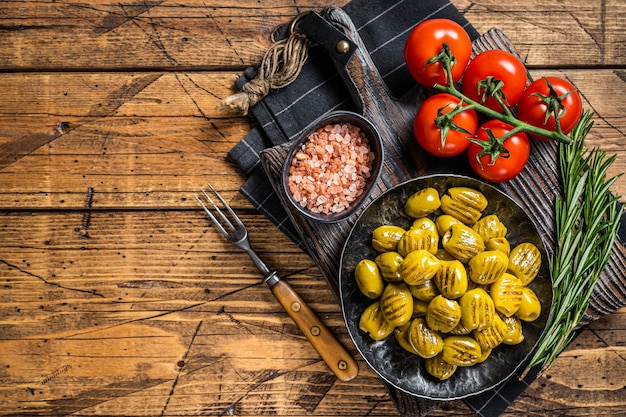 Aceitunas orgánicas asadas con hierbas en plato Fondo de madera Vista superior Espacio de copia