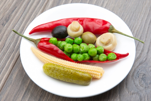 Aceitunas, pepino encurtido, pimiento, champiñones y maíz en una ensalada en un plato. alimentos y verduras. dieta y adelgazamiento