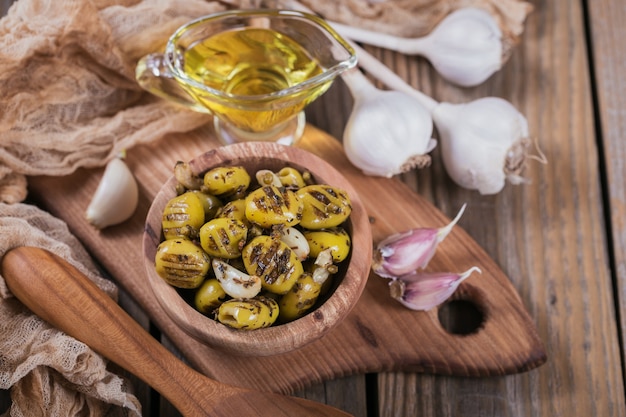 Aceitunas a la plancha con ajo, aceite de oliva y especias sobre fondo de madera rústica