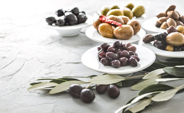 aceitunas seleccionadas de diferentes tamaños y colores en un cuenco de cerámica sobre un fondo de hormigón