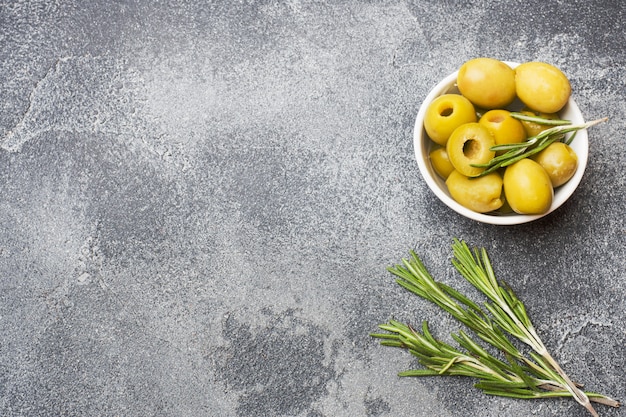 Aceitunas verdes en cuencos en la mesa oscura. Copia espacio