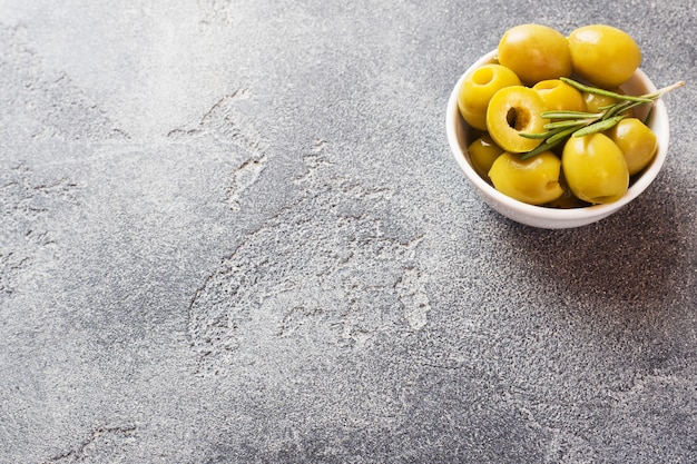 Aceitunas verdes en cuencos en mesa oscura