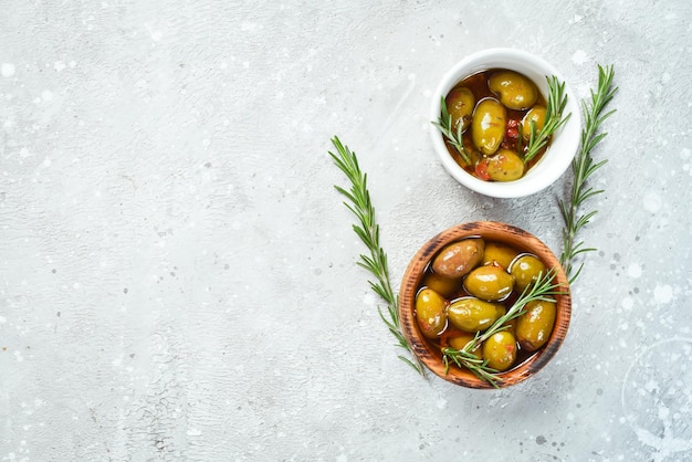 Aceitunas verdes en escabeche en aceite En un recipiente sobre un fondo de piedra gris Espacio libre para texto