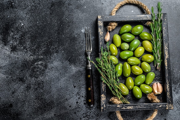 Aceitunas verdes frescas en bandeja de madera con tomillo