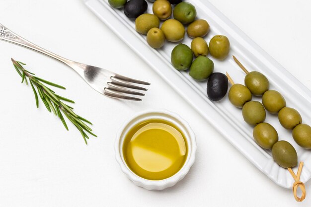 Aceitunas verdes en un plato blanco Aceite de oliva en un tazón pequeño