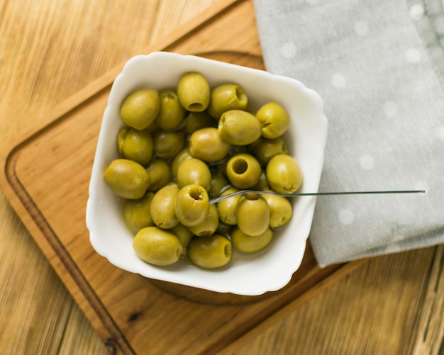 Aceitunas verdes en un plato blanco sobre un fondo de madera