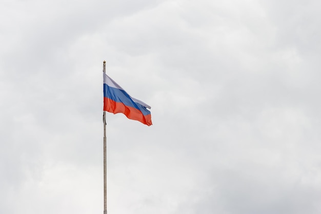 Acenando a bandeira da Rússia contra o céu nublado sombrio