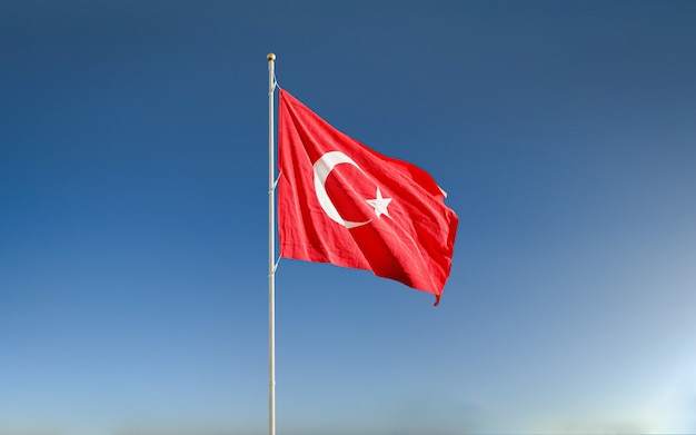 Acenando a bandeira da Turquia no céu azul