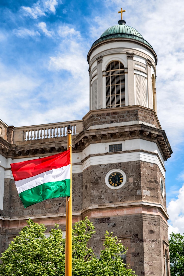 Foto acenando a bandeira húngara no mastro da basílica de esztergom ao fundo
