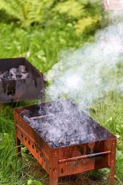 Acendendo fumaça e fogo em uma velha churrasqueira de metal enferrujado