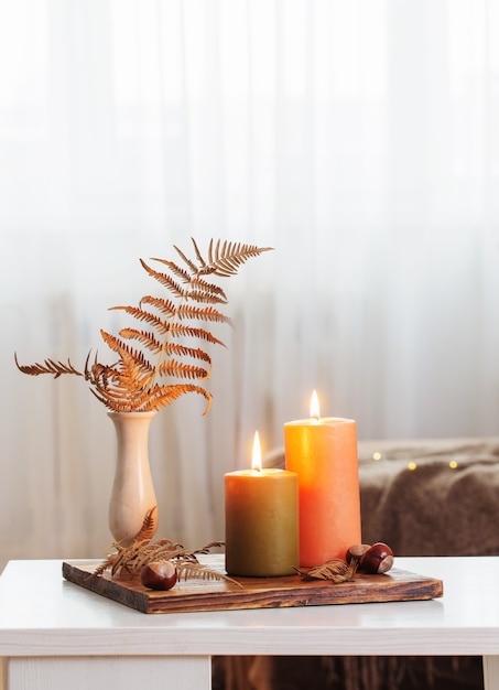 Acendendo velas com decoração de outono na mesa branca em casa