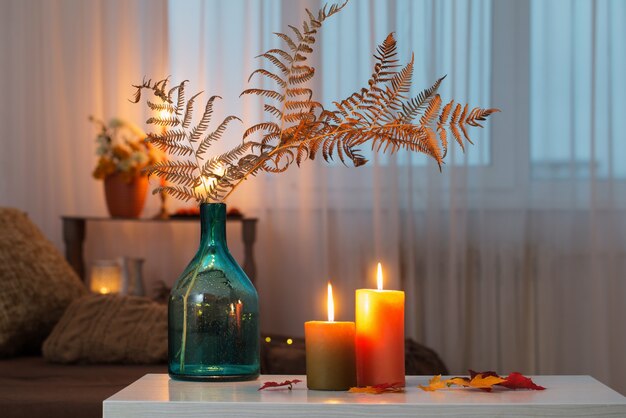 Acendendo velas com decoração de outono na mesa branca em casa