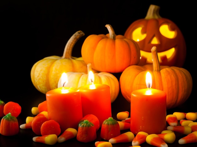 Acendeu velas laranja com pequenas abóboras e jack-o'-lantern em fundo preto.