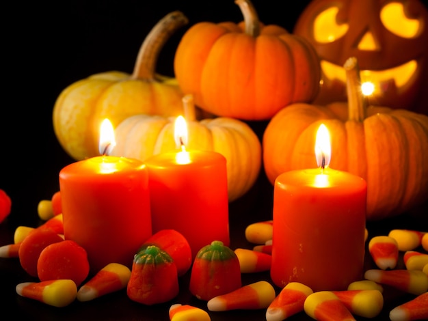 Acendeu velas laranja com pequenas abóboras e jack-o'-lantern em fundo preto.