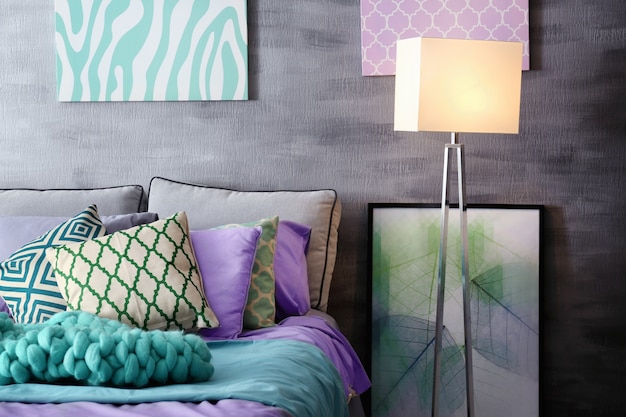 Foto acento lila en interiores modernos. cómoda cama con almohadas y cuadros en la habitación
