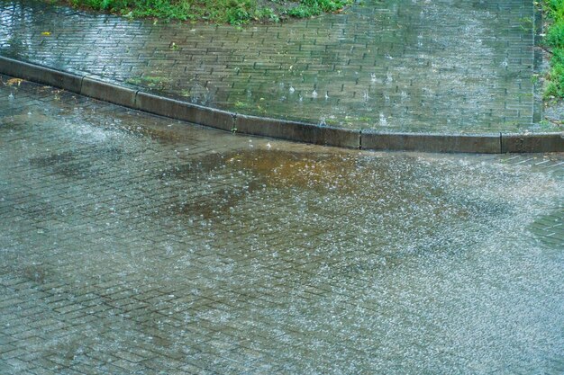 La acera y la carretera húmedas en la ciudad después de la lluvia Las salpicaduras de agua en la carretera durante un aguacero Grandes gotas de lluvia en la superficie de la tierra
