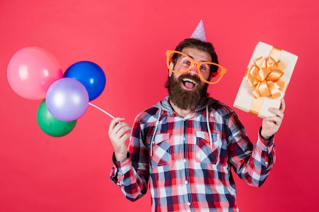 Se acerca el gran momento. La mejor fiesta de diversión multicolor para la jubilación. Hombre alegre con barba, sostenga el hipster actual, sonriendo con globo. Celebrando la fiesta feliz. Elementos de fiesta y objetos de vacaciones.