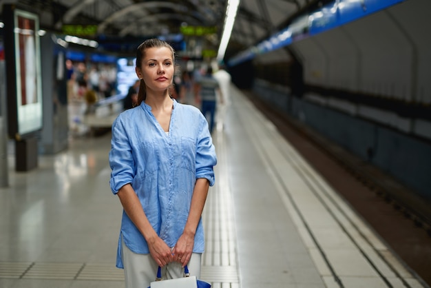 Se acerca el tren - mujer joven esperando su conexión en una moderna estación de tren