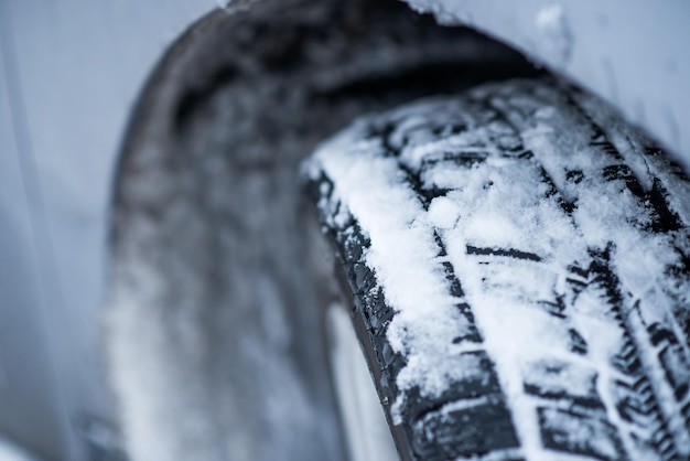 Foto acercamiento de los neumáticos de invierno en una carretera cubierta de nieve en los fríos meses de invierno.