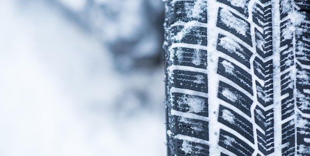 Foto acercamiento de los neumáticos de invierno en una carretera cubierta de nieve en los fríos meses de invierno.