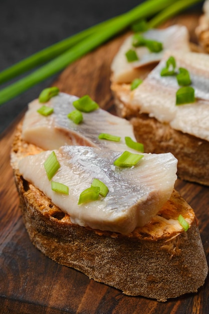 Acercamiento de sándwich con arenque salado y cebolla verde