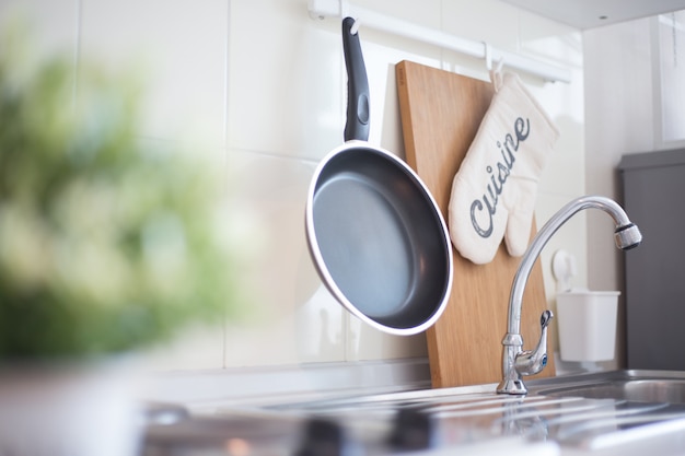 Foto acessórios de cozinha pendurados no trilho do telhado na parede branca