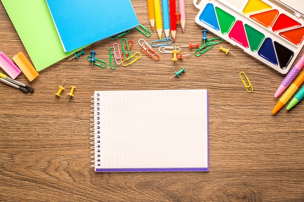 Acessórios de escola brilhante, artigos de papelaria em uma mesa de madeira. Vista de cima