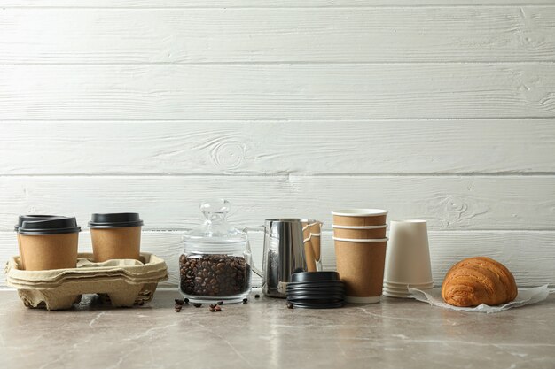 Acessórios de hora do café na mesa cinza contra um fundo branco de madeira