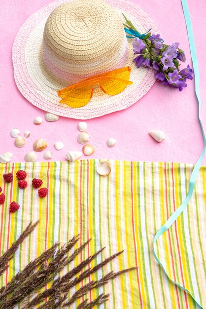 Acessórios de lazer de verão em um fundo rosa com conchas.