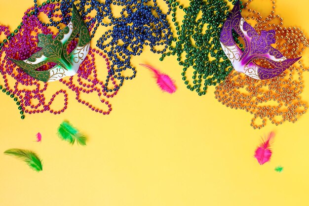 Acessórios de mardi gras colocados em plano em fundo amarelo brilhante espaço de cópia de vista superior quadro com tradicionais contas mardi gras máscaras penas plano conceito de férias de carnaval acima