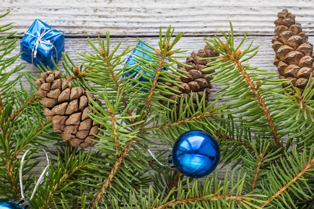 Acessórios de Natal em ramos de azul, cone e abeto em fundo branco de madeira