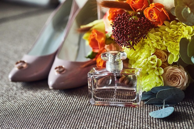 Acessórios de noiva, como anel de buquê de sapatos e perfume, estão sobre uma mesa