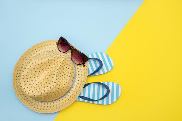Acessórios de praia chapéu de palha óculos de sol chinelos amarelo fundo azul linho espaço de cópia de fundo