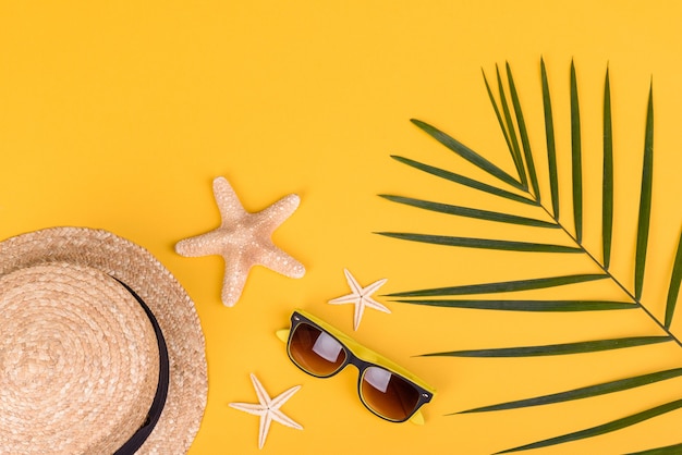 Acessórios de praia: óculos e chapéu com conchas e estrelas do mar sobre fundo colorido. Fundo de verão