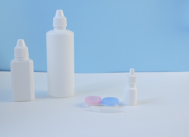 Acessórios e produtos para o cuidado de lentes de contato em fundo branco e azul. Composição horizontal. Primeiro plano.